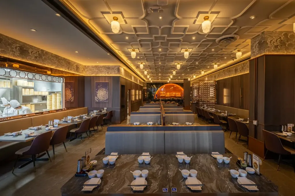 The Paradise Dynasty dining room, with marble tables, hanging lights, and the open kitchen