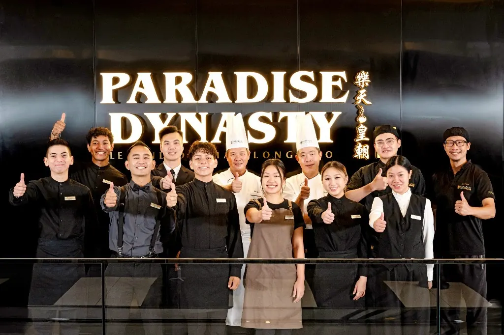 The Paradise Dynasty team in front of the illuminated restaurant sign